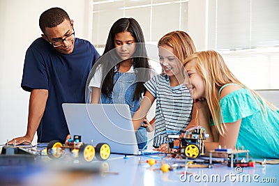 Three Female Students With Teacher Building Robot Vehicle In After School Computer Coding Class Stock Photo