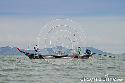 Three Fishermen on boat draw up a net to catch fish on the beach in morning . Editorial Stock Photo