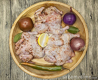 Three fresh raw chicken on a wooden tray with lemon and chilli on the wooden background Stock Photo