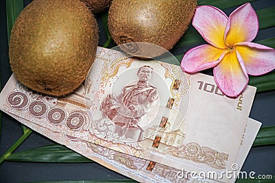 Three Fresh Raw Exotic Tropical Kiwi Fruits also called Chinese Gooseberrys with Thai National Currency Bahts Stock Photo