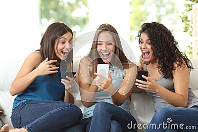 Three friends amazed watching a smart phone Stock Photo