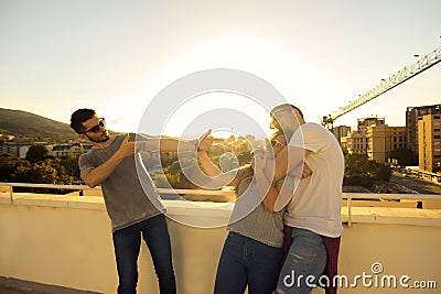 YOUNG PEOPLE CHILLING OUT AND HAVING FUN ON A BUILDING ROOFTOP Stock Photo