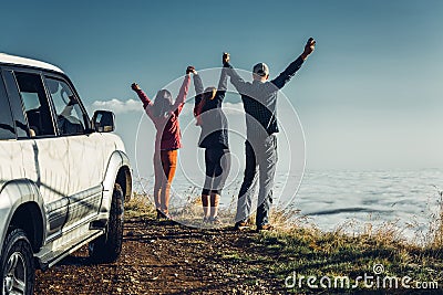 Three friends joined hands and raised their hands up, enjoying the view of Outdoor.Vacations Journey Concept Stock Photo