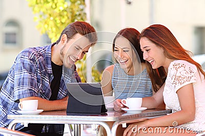 Three friends watching tv or social media in a tablet Stock Photo