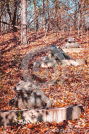 Three frog statues sitting in autumn leaves Editorial Stock Photo