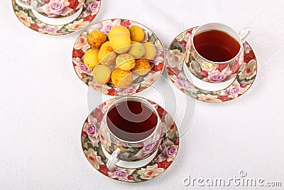 Three full porcelain teacups with hot tea and with floral pattern and plate with wild apricots Stock Photo