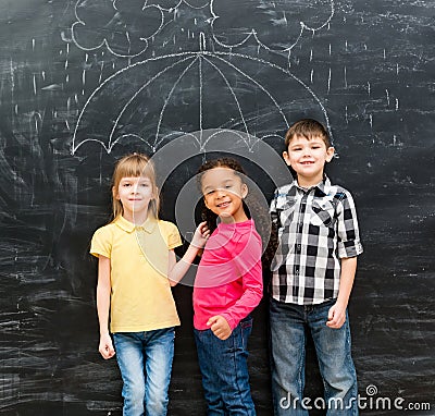 Three funny children with umbrella drawn on the blackboard Stock Photo