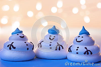 Three funny meringue snowmen under a festive garland. Stock Photo