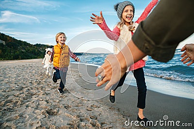 Three funny smiling laughing white Caucasian children kids friends playing running to mother parent adult on ocean sea beach Stock Photo