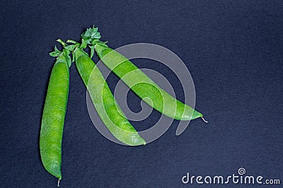 Three garden pea pods on a black background Stock Photo