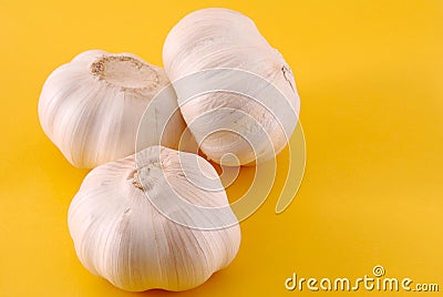 Three garlics on yellow Stock Photo