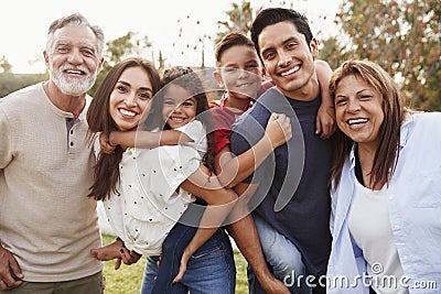 Three generation Hispanic family standing in the park, smiling to camera, selective focus Stock Photo