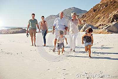 Three generation white family walking together on a sunny beach, kids running ahead Stock Photo