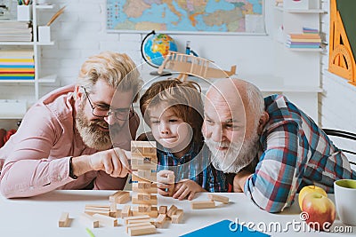 Three generations of active men playing in living room. Laughing grandparent with son and grandchild relaxing spending Stock Photo