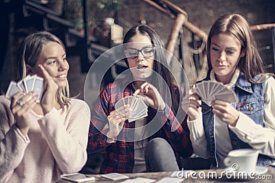 Three girls in cafe playing game cards. Stock Photo