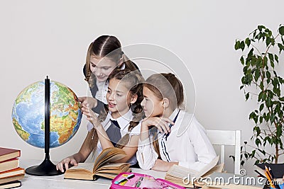 Three girls in the classroom studying geography globe of planet Earth Stock Photo