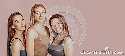 Three girls in comfortable home clothes together on a pink background. Women smile and have fun. The concept of spa treatments, Stock Photo