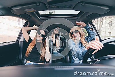 Three girls driving in a convertible car and having fun, listen music and dance Stock Photo