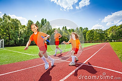 Three girls with one relay baton running Stock Photo