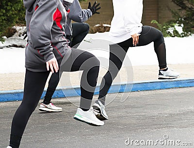 Three girls performing track warm up drills in parking lot Stock Photo