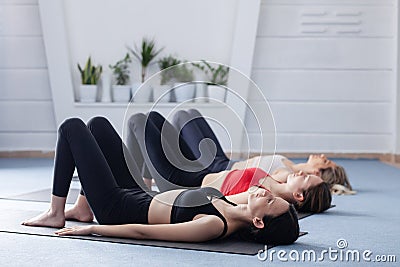 Three girls practicing yoga. Yoga instructor with her students meditating in a studio Stock Photo