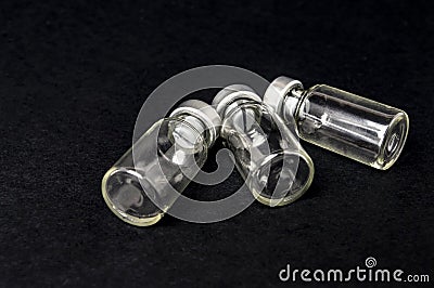 Glass bottle from the vaccine lie on a black background closeup Stock Photo