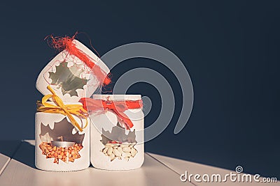 Three glass jars, decorated with a candlestick, with a window in the shape of a maple leaf, with a candle and peas inside. The Stock Photo