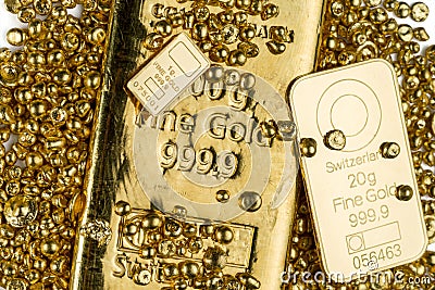 Three gold bars of different weights lie in a pile of gold granules. Stock Photo