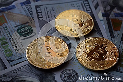 Three Gold Bitcoin Coins on US Dollars Stock Photo