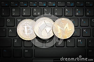 Three golden crypto currency coins on black keyboard Editorial Stock Photo