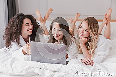 Three gorgeous women 20s wearing white bathrobe lying in luxury Stock Photo