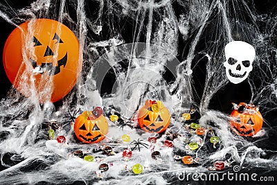 Three halloween pumpkins with candies inside, cobweb, candies everywhere spiders and two balloons Stock Photo