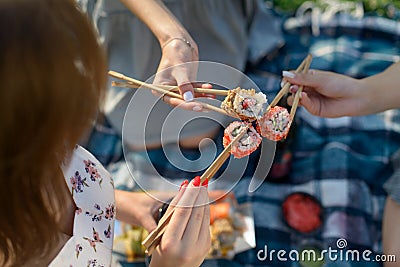 Three hands with chopsticks and sushi. Top view Stock Photo