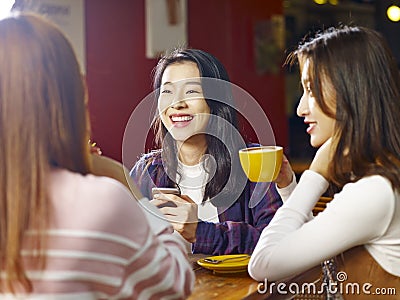 Three young asian women chatting talking in coffee shop Stock Photo