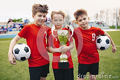 Three Happy Cheerful Kids of Sports Soccer Team. Boys Football Players Holding Trophy at the Stadium Stock Photo