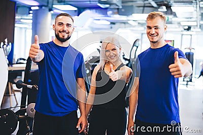 Three happy people at the gym showing thumbs up. Stock Photo