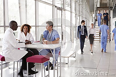 Three healthcare workers talking in a busy modern lobby Stock Photo