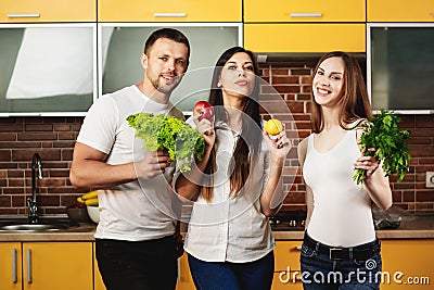 Three healthy, thin beautiful people hold in their hands and promote healthy food, vegetables and fruits. Stock Photo