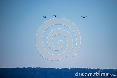Three helicopters fly over tree-lined landscape Stock Photo