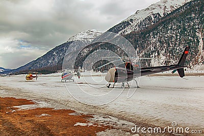 Three helicopters on a row waiting to take off in the alps switzerland Stock Photo