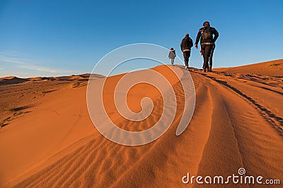 Three hikers are goiong up on the sand Dune in Erg Chebbi desert, Morocco Editorial Stock Photo