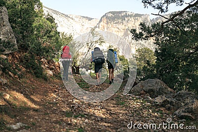 Three hikers on trail in mountains Stock Photo