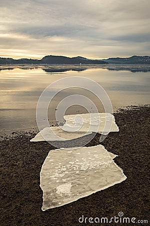 Three ice floes on dark sand on Norwegian beach. Calm sea, mist and fog. Hamresanden, Kristiansand, Norway Stock Photo
