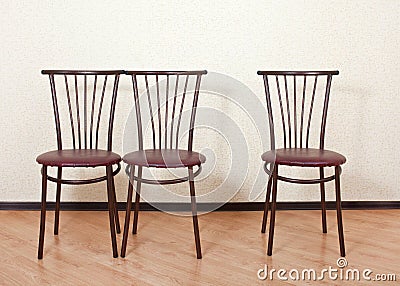 Three identical chair next against the wall Stock Photo