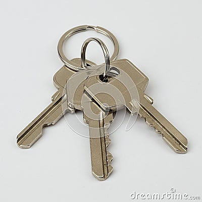 Three identical metallic keys are connected by a circular keyring. Stock Photo