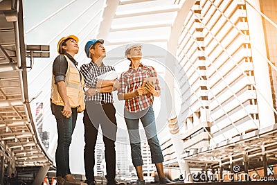 Three industrial engineer standing and looking to right side wear safety helmet with holding inspection and digital tablet Stock Photo