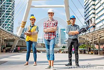 Three Industrial engineer wear safety helmet engineering standing with arms crossed holding inspection tablet and smile Stock Photo