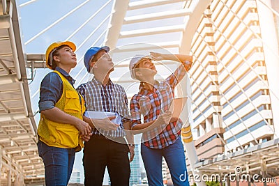 Three industrial engineer wear safety helmet and holding tablet engineering working and talking Stock Photo