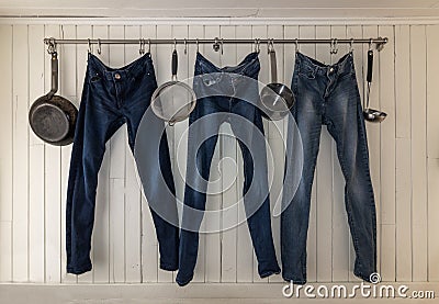 Three jeans hanging on a kitchen rail to dry Stock Photo