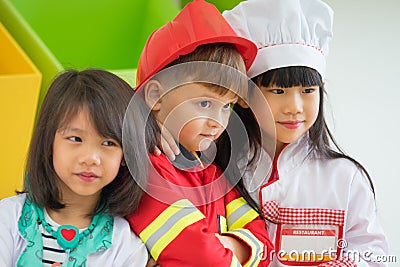 Three kid dress up to fireman and doctor and chef at roll play classroom,Kindergarten preschool education concept Stock Photo